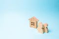 three figures of people and a wooden house on a blue background. The concept of affordable housing and mortgages for buying a home