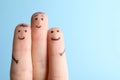 Three fingers with drawings of happy faces on light blue background, space for text Royalty Free Stock Photo