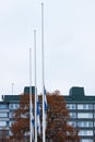 Three finnish flags lowered to half mast on the occasion of mourning at cloudy autumn day