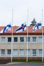 Three finnish flags lowered to half mast on the occasion of mourning at cloudy autumn day