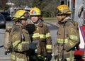 Three firefighters discuss firefighting strategy during a house fire