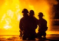 Three firefighters kneeling in front of fire Royalty Free Stock Photo