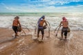 Three fishermans fishing mole crab in Mai Khao beach near Phuket Airport