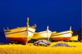Three fishing boats on a sandy beach in the evening against the background of the sea. Royalty Free Stock Photo