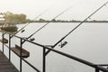 Three fishing rods with reels, spinning stands in a row on the brackets, catching fish on the river Royalty Free Stock Photo