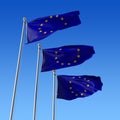 Three flags of Europe Union against blue sky.