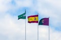 Three flags: Spain, Andolusia and Malaga against the blue sky with white clouds. Royalty Free Stock Photo