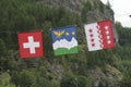 Three flags of Switzerland, Wallis and Val d`HÃÂ©rens next to each other in front of a mountain and trees Royalty Free Stock Photo