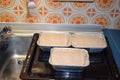 three FleischkÃ¤se ready to bake, with old fashioned kitchen background