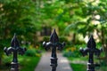 Three Fleur De Lis on a Fence in front of a Garden