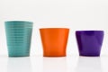 Three flower pots in turquoise, orange and purple colors isolated on a white background with a clipping path. Royalty Free Stock Photo