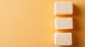 Three fluffy marshmallows are neatly stacked on a vibrant yellow surface, creating a delightful and colorful visual