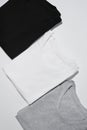 Three folded monochrome t shirts gray, black and white isolated over gray background Royalty Free Stock Photo