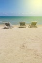 Three folding beach chairs on the beach with sea, bright sky and yellow light in the background at Koh Mak in Trat, Thailand.