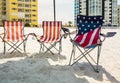 Three folding beach chairs under shade on beach