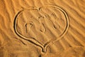 Three footprint and heart on sand