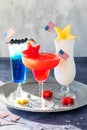 Three fourth of July cocktails garnished with American flags and fresh fruit.