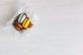 Three French macarons in gift box on a white wooden table. Chocolate, yellow and light blue macarons