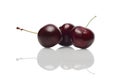 Three fresh cherries with reflection on glossy surface Royalty Free Stock Photo