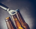 Three fresh cold beer ale bottles with drops and stopper open with bottle opener Royalty Free Stock Photo