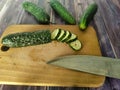 Three fresh cucumbers on a wooden table.  Sliced on a wooden board Royalty Free Stock Photo