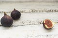 Three fresh figs on a wooden white table. One fig is cut in halves and its flesh is visible. Located in a group. Royalty Free Stock Photo