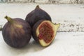 Three fresh figs on a wooden white table. One fig is cut in halves and its flesh is visible. Located in a group. Royalty Free Stock Photo