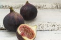 Three fresh figs on a wooden white table. One fig is cut in halves and its flesh is visible. Located in a group Royalty Free Stock Photo