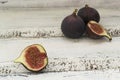 Three fresh figs on a wooden white table. One fig is cut in halves and its flesh is visible. Located in a group Royalty Free Stock Photo