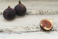 Three fresh figs on a wooden white table. One fig is cut in halves and its flesh is visible. Located in a group. Royalty Free Stock Photo
