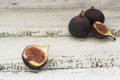 Three fresh figs on a wooden white table. One fig is cut in halves and its flesh is visible. Located in a group Royalty Free Stock Photo