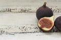 Three fresh figs on a wooden white table. One fig is cut in halves and its flesh is visible. Located in a group Royalty Free Stock Photo