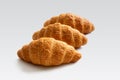Three fresh French croissants in a row on a white background