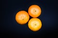 Three fresh oranges on a black table