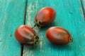 Three fresh organic red and black tomatoes on old turquoise tabl Royalty Free Stock Photo