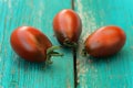 Three fresh organic red and black tomatoes on old turquoise tabl Royalty Free Stock Photo