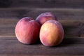 Three fresh peaches on a wooden table Royalty Free Stock Photo