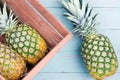 Three fresh pineapples, two in a wooden crate
