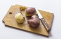 Three fresh potatoes and a knife ,one heart-shaped potato, on a chopping Board Royalty Free Stock Photo