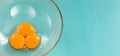 Three fresh raw egg yolks in a glass bowl prepared for whipping on a blue background. Top view Royalty Free Stock Photo