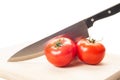 Three fresh and red tomatoes and a steel knife Royalty Free Stock Photo
