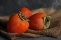 Three fresh ripe persimmon fruit on burlap Royalty Free Stock Photo