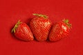 Three fresh strawberries on red textile background