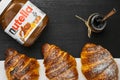 Three freshly baked croissant with nutella or jam on a black background. Traditional french or italian breakfast