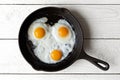 Three fried eggs in cast iron frying pan isolated on white paint Royalty Free Stock Photo