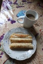 three rolled pancakes on a plate with a cup of coffee top view Royalty Free Stock Photo
