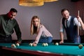 three friendly people looking at balls on pool billiards table Royalty Free Stock Photo