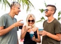 Three friends cheerful company rest on a tropical beach and drink cocktails, very, magazine concept Royalty Free Stock Photo