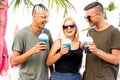 Three friends cheerful company rest on a tropical beach and drink cocktails, very, magazine concept Royalty Free Stock Photo