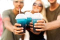 Three friends cheerful company rest on a tropical beach and drink cocktails, very, magazine concept Royalty Free Stock Photo